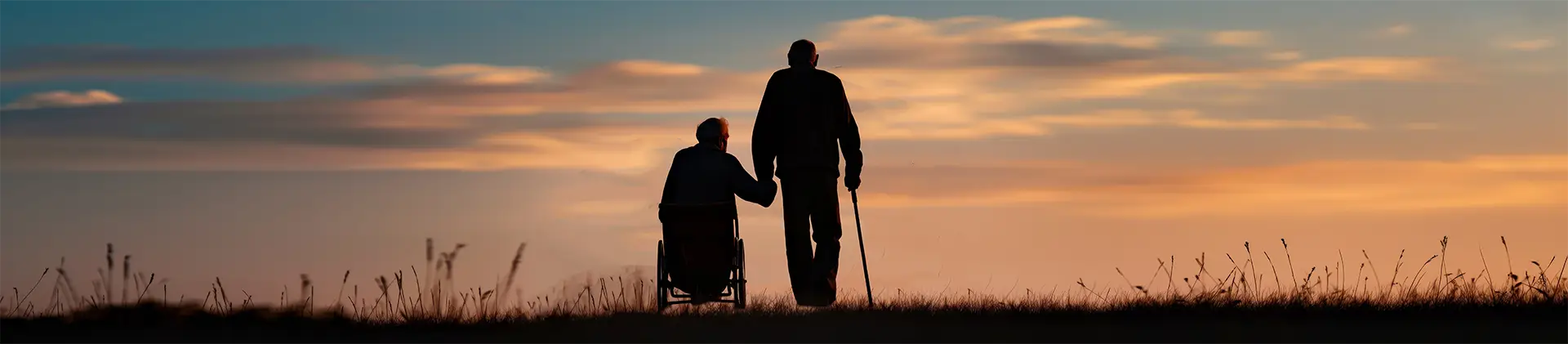 Older adult and caregiver walking together at sunset