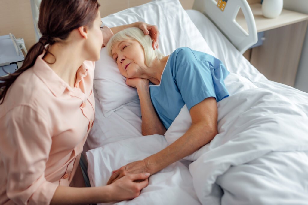 daughter comforting elderly mother during end-of-life care in hospital bed