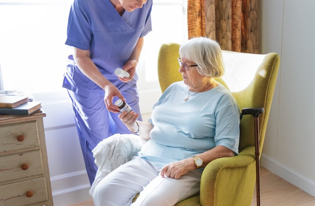 Caregiver assisting senior woman with medication management in a residential care home