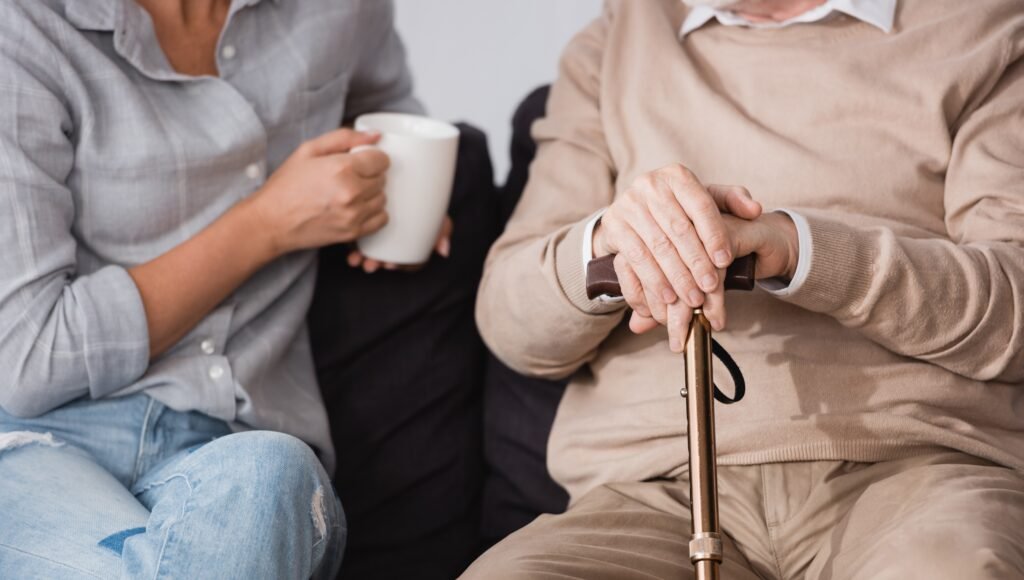 Adult child talking with older parent holding a cane during a supportive conversation about care decisions