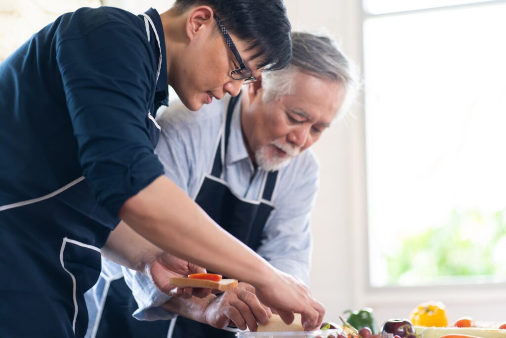 Older adult with Parkinson's disease preparing a meal with a caregiver at home