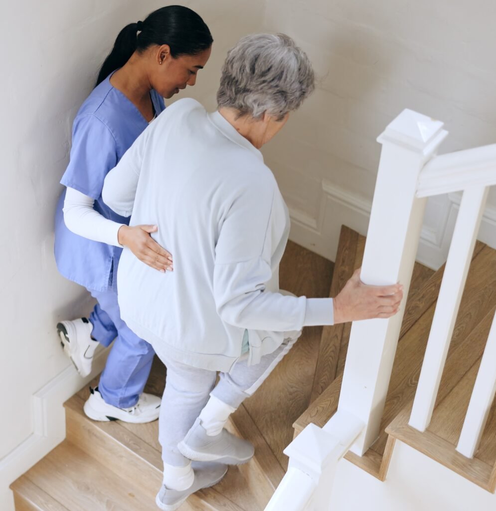 Older adult struggling with stairs at home while caregiver provides support