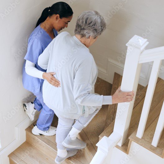 When is it time for assisted living – older adult struggling with stairs at home while caregiver provides support