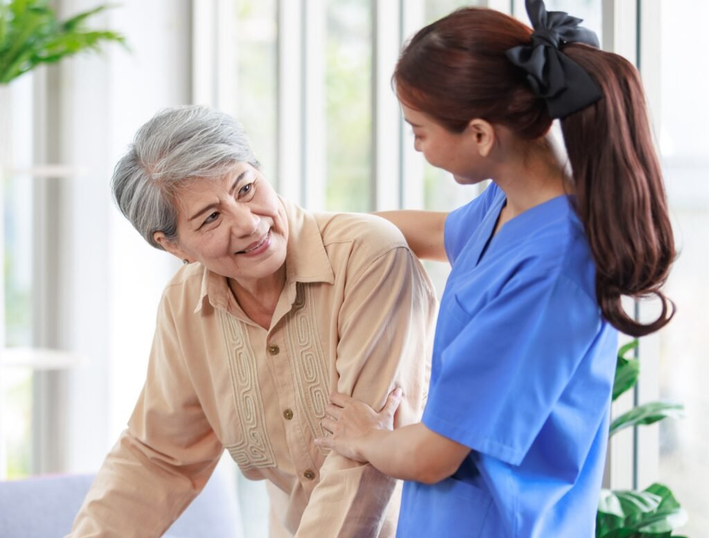 Caregiver assisting elderly woman with mobility in assisted living community