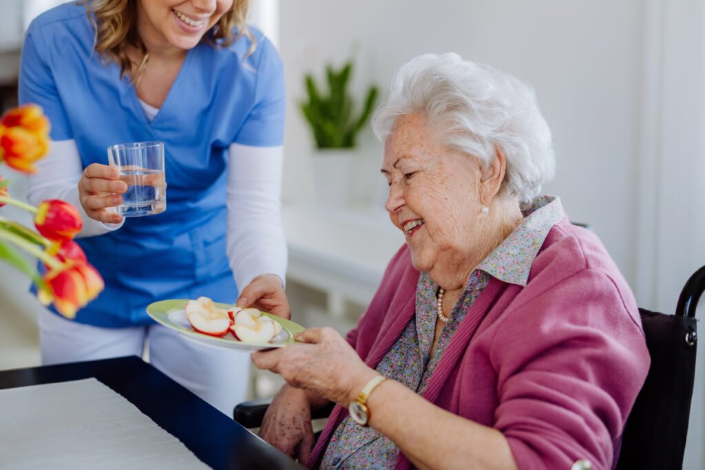 caregiver providing in-home care by assisting senior with meal and hydration at home