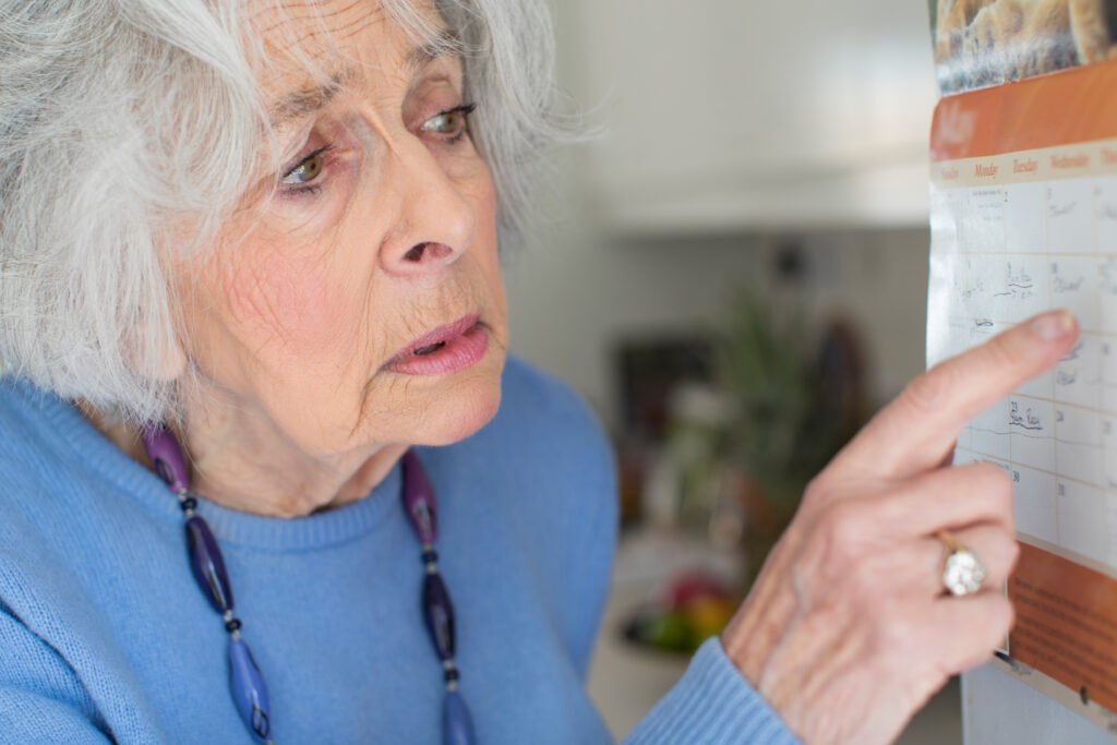 senior woman looking confused at calendar showing memory loss and need for memory care support