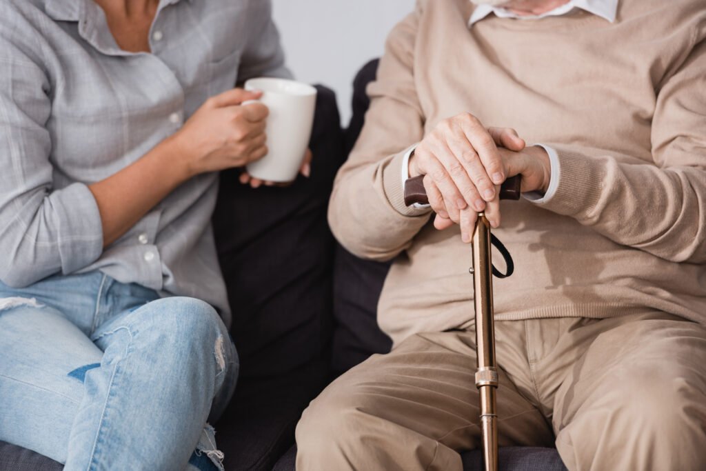 Adult child talking with older parent holding a cane during a supportive conversation about care decisions