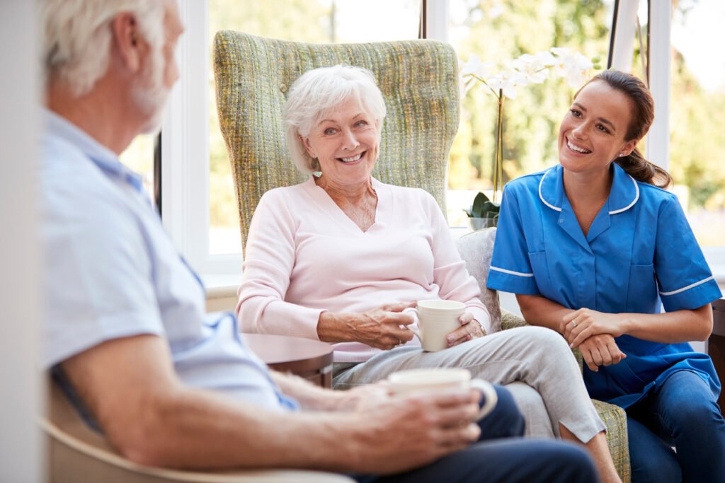 Caregiver speaking with elderly couple while family observes during assisted living tour