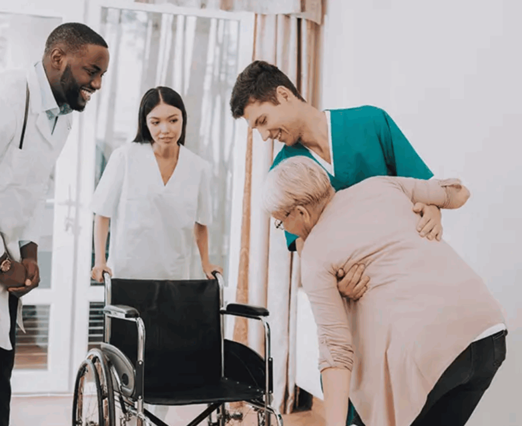 example of what a nursing home looks like with staff helping elderly resident into wheelchair