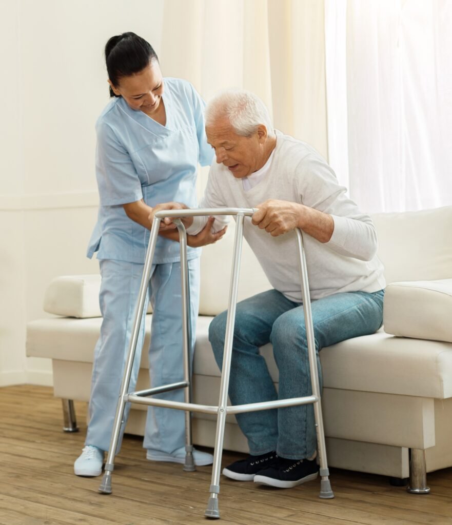 Caregiver helping elderly man use walker for mobility support at home