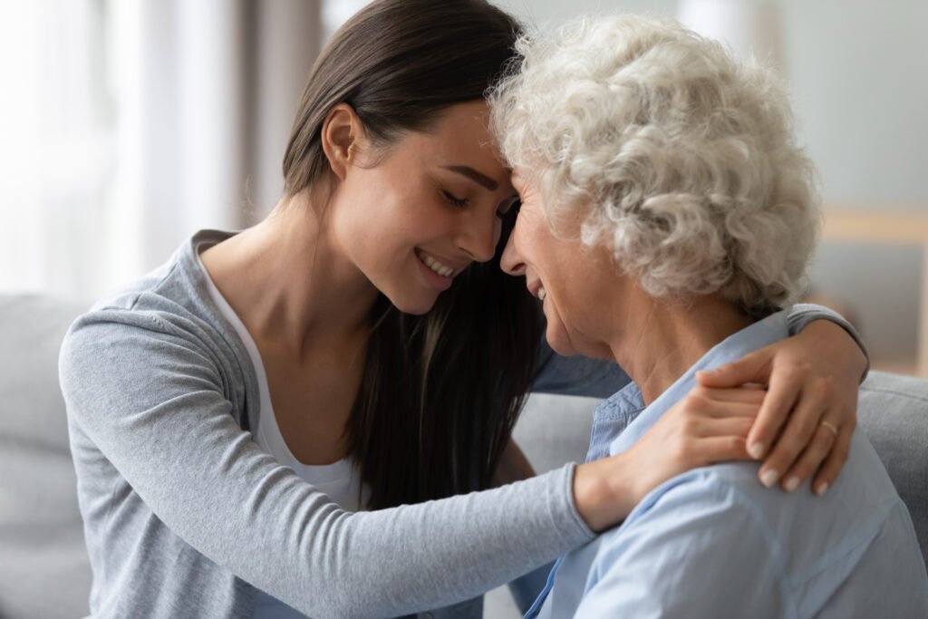 Adult daughter comforting and embracing her elderly mother living with Alzheimer’s disease