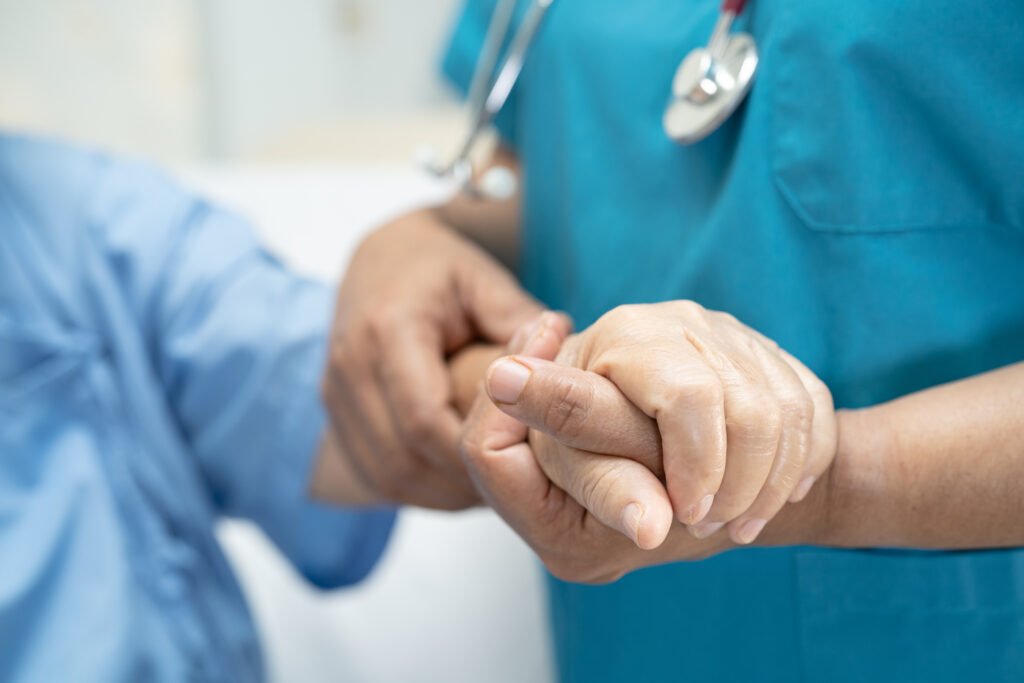 Hospice nurse holding an elderly patient’s hand during compassionate hospice care