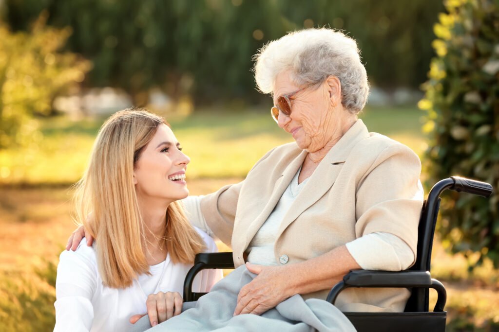 Family caregiver spending quality time with an elderly loved one using a wheelchair outdoors