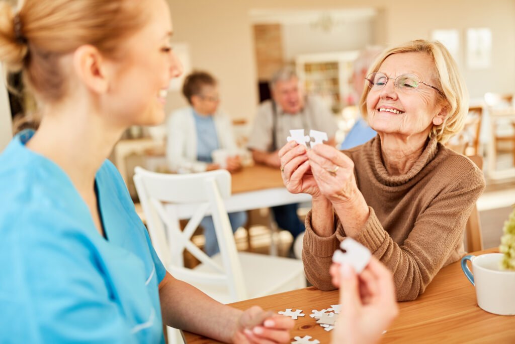 Senior woman participating in a memory care puzzle activity with caregivers in a supportive dementia care community