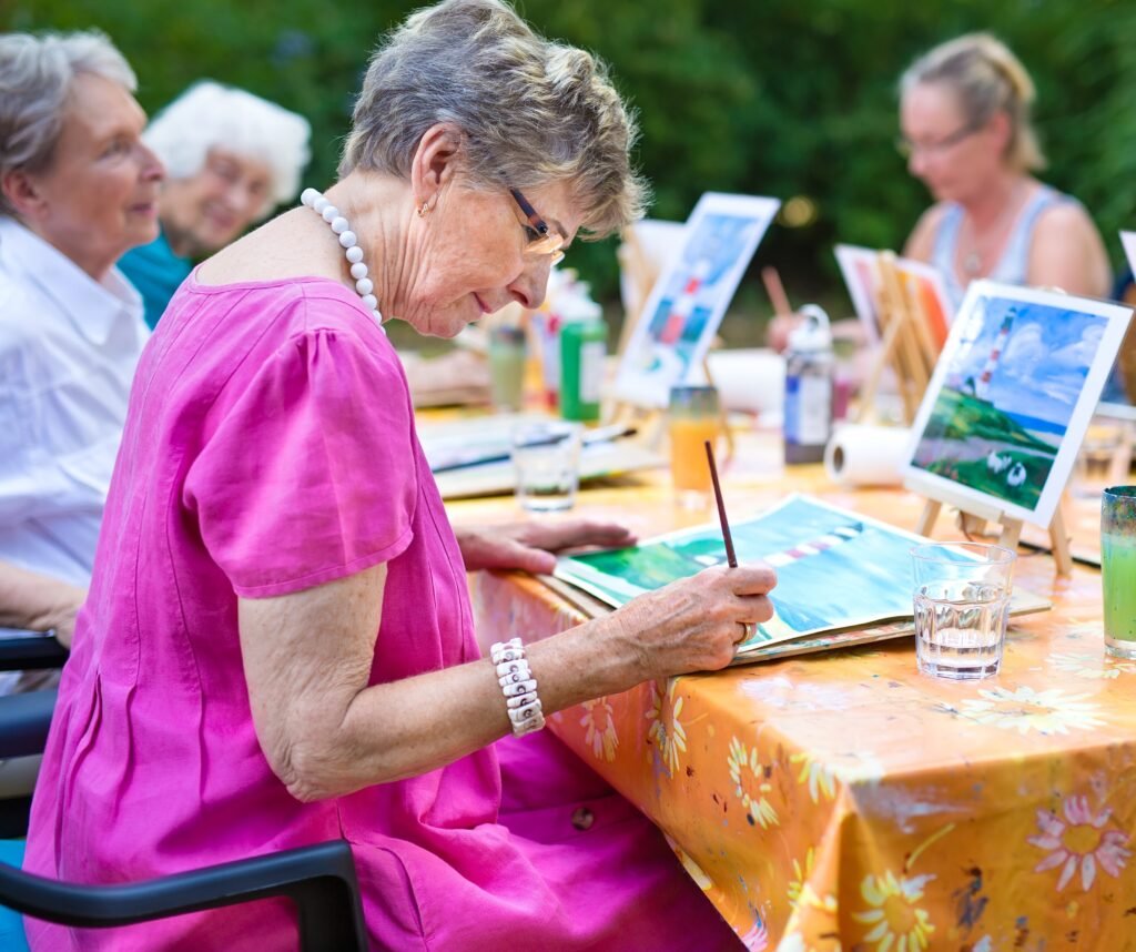 Older adults participating in a painting and creative activity together outdoors