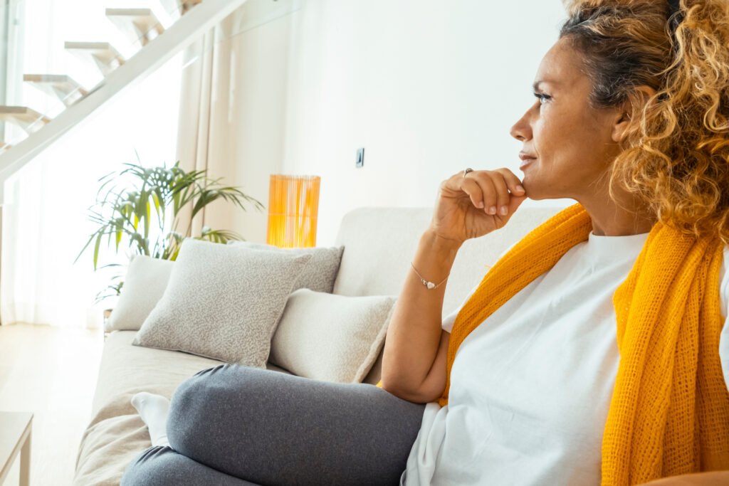 Family caregiver sitting thoughtfully at home while coping with anticipatory grief, uncertainty, and the emotional challenges of caring for a loved one.