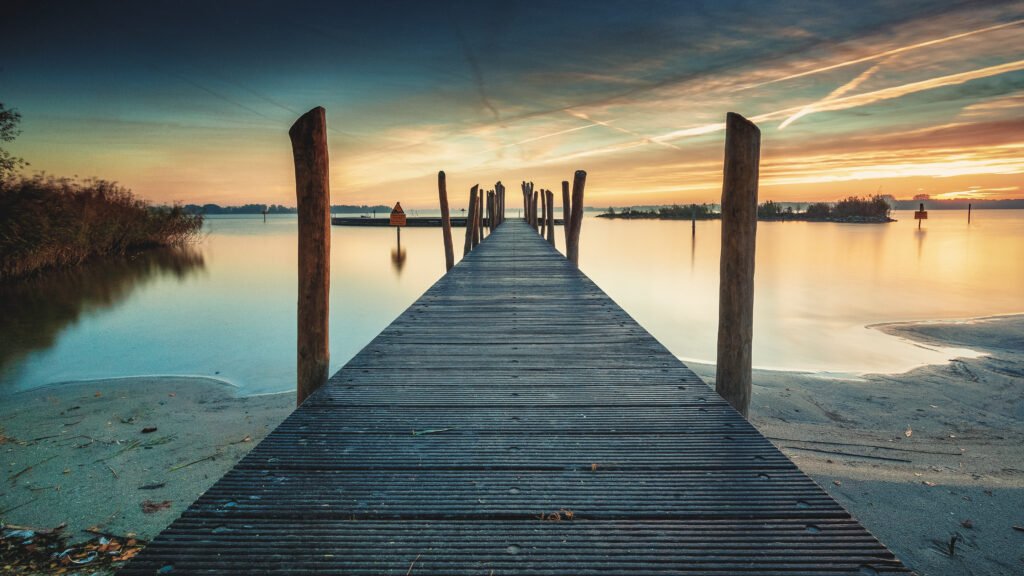 Wooden pier extending into calm water at sunset, symbolizing hope, reflection, and the journey through anticipatory grief.