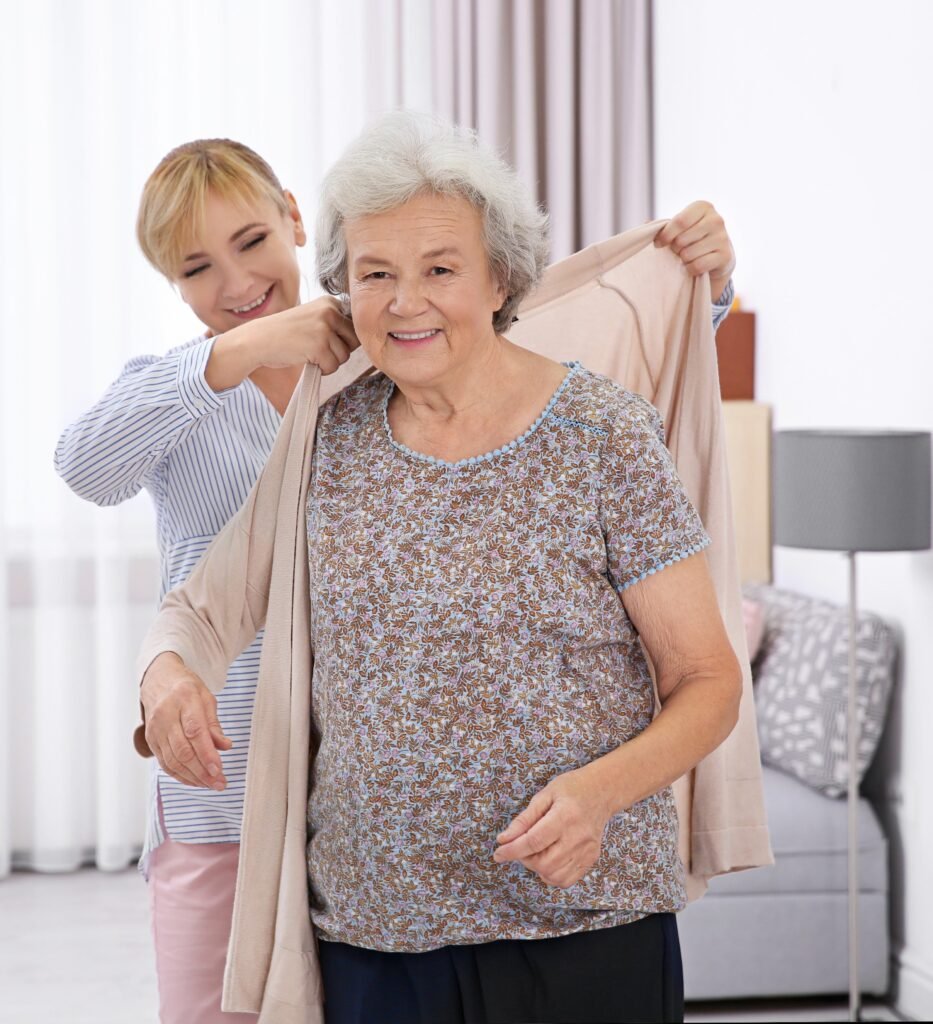 Caregiving while working: Adult daughter helping her aging mother get dressed at home as part of everyday caregiving.
