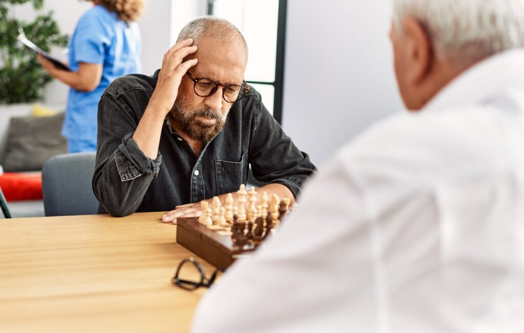 Senior participating in a chess game during a short-term assisted living stay while exploring life in an assisted living community.