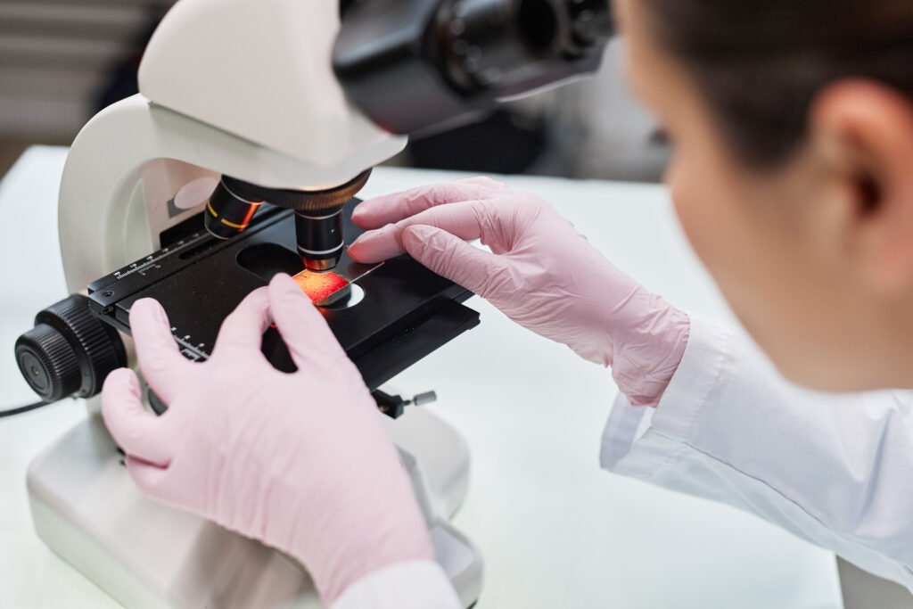 Lab worker examining a sample under a microscope during laboratory research.