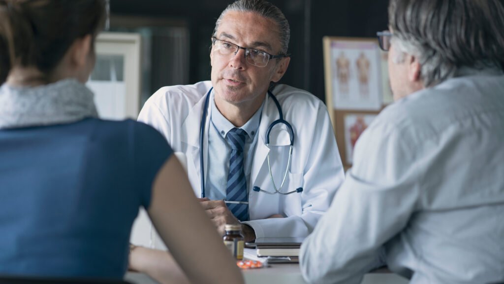 Doctor speaks with an older adult and family member about possible Alzheimer’s concerns.